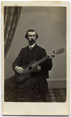 an old black and white photo of a man with a guitar in his lapel