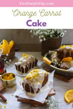 an orange carrot cake with icing and lemons on the table next to it