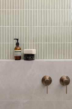 two soap dispensers on the side of a tiled wall