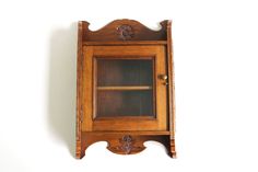 an old wooden cabinet with glass doors on the front and side, against a white wall