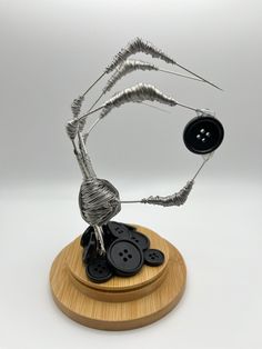 a metal sculpture on top of a wooden base with buttons and wires attached to it