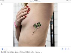 a woman's stomach with a small tattoo on her left side, which has four leaf clovers attached to it