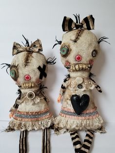 two stuffed animals dressed in clothes with bows and striped stockings, standing next to each other