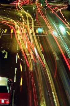 cars driving down the street at night with long exposures on their headlights and taillights