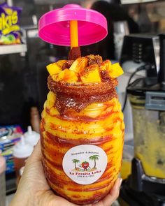 a person holding up a jar filled with food and a pink lid on top of it