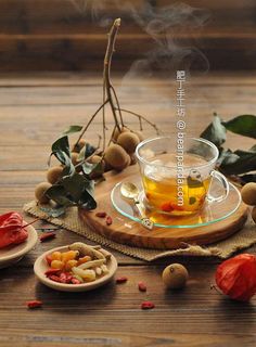 a glass cup filled with tea sitting on top of a wooden table next to nuts