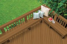 an overhead view of a wooden deck with pillows on it and green grass in the background