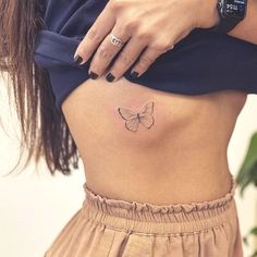 a woman's stomach with a small butterfly tattoo on her side ribcage