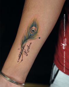 a woman's wrist with a peacock feather on it and the word love written in cursive writing