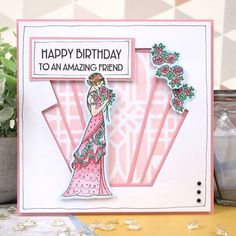 a birthday card with a woman in a pink dress and flowers on the side, next to a potted plant