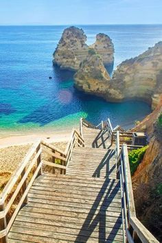 stairs leading down to the beach and ocean with two large rocks in the water behind them