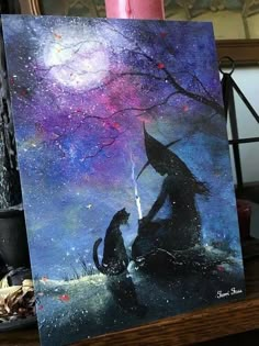 an easel with a painting of a witch and her cat on it