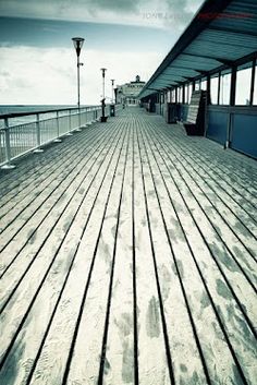 an empty pier with benches and lights on it