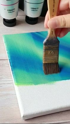 someone using a paint brush to paint a canvas