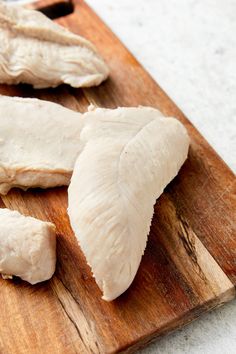 two pieces of chicken on a wooden cutting board