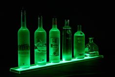 an assortment of liquor bottles lit up in the dark with green light from below them