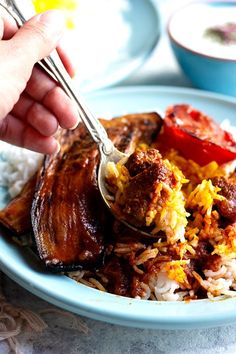 a plate with rice, meat and vegetables being spooned into it by a person's hand