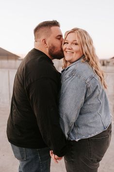 a man and woman standing next to each other with their arms around each other as they kiss