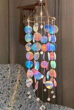 a wind chime hanging from the ceiling in front of a window with white curtains