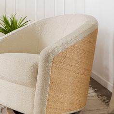 a white chair sitting on top of a wooden floor next to a potted plant