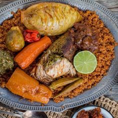 a blue plate topped with meat, vegetables and rice next to a slice of lime