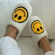 someone is wearing slippers with smiley faces on their feet and they are sitting on a white couch