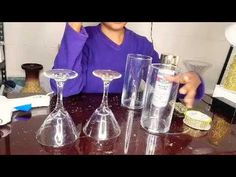 a woman sitting at a table with three wine glasses and two empty bottles on it