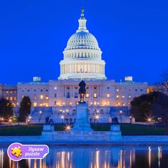 the capitol building is lit up at night with lights reflecting in the water below it