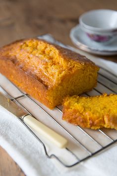 a loaf of bread sitting on top of a cooling rack next to a cup and saucer