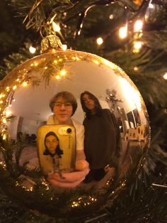 two women standing in front of a christmas ornament with an image on it