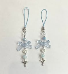 pair of earrings with blue glass beads and silver cross pendants on light blue cord