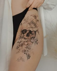 a woman's thigh with a skull and flowers tattoo on it