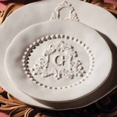 two white plates sitting on top of a wooden plate holder with the letter g in it