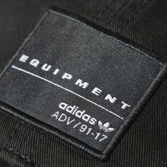 a label on the back of an adidas sweatpants with white letters that read equipment