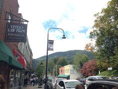 people are walking down the sidewalk in front of shops and businesses on a sunny day