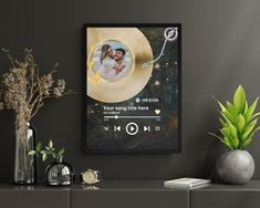 a black and gold photo frame with a couple on it next to some vases