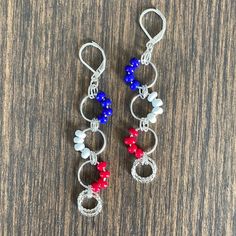 two red, white and blue beaded earrings on a wooden table with silver earwires