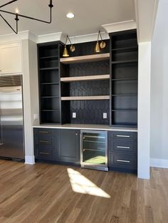 an empty kitchen with black cabinets and stainless steel appliances in the middle of the room