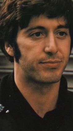 a close up of a person wearing a black shirt and looking at the camera with a serious look on his face