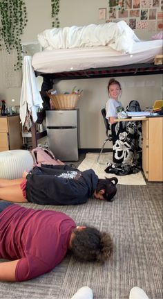 two people laying on the floor in front of a bunk bed