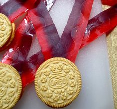 three cookies sitting on top of a cutting board next to red ribbon and some candy