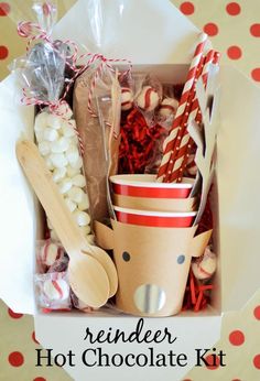 a cup filled with candy and wooden spoons next to other items in a box