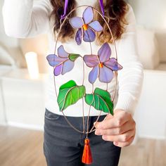 a woman holding up a piece of art made out of stained glass with flowers on it