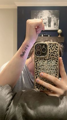 a woman holding up her phone case with a tattoo on the back of her arm