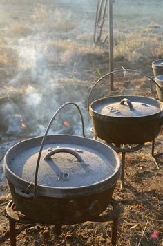 two large pots sitting on top of an open fire pit