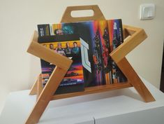 a wooden tray with magazines in it sitting on top of a white counter next to a wall