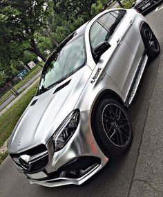 a silver car parked on the side of a road next to some trees and grass