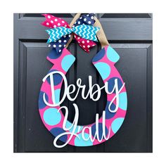 a door hanger with the words derby ball painted on it and a polka dot bow