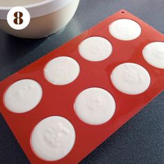 a red tray with eight white circles on it next to a bowl and measuring spoon