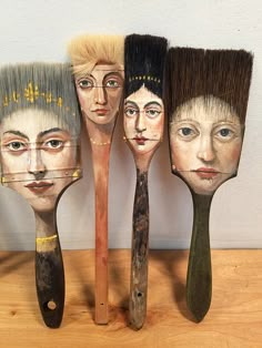 four wooden brushes with faces painted on them